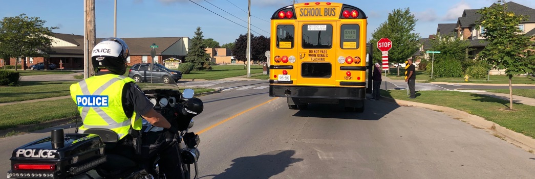 an officer on a motorcycle trailing behind a school bus